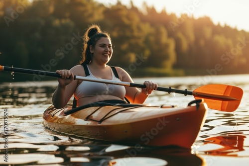 Cheerful plus-size young woman kayaking on a serene lake at sunset.