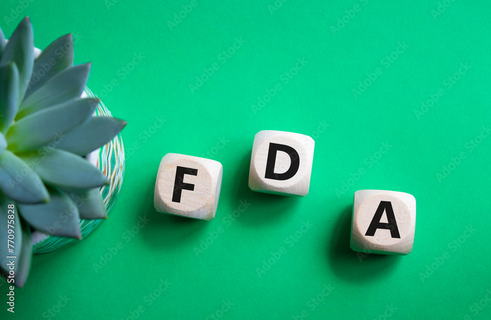 FDA - Food Drug Administration symbol. Wooden cubes with word FDA. Beautiful green background with succulent plant. Medical and Food Drug Administration concept. Copy space. FDA - Food Drug Administration symbol. Wooden cubes with word FDA. Beautiful green background with succulent plant. Medical and Food Drug Administration concept. Copy space.