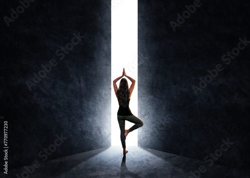 Woman in meditation position while a door opens and light enters