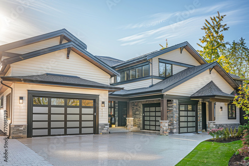 High-end modern-style home, newly built, with a two-car garage, surrounded by elegant ivory siding and a natural stone wall trim for a distinguished look.