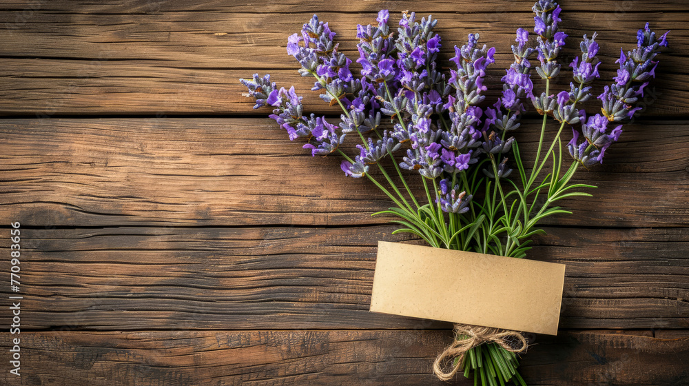 Bouquet of cut fresh branches of purple lavender (Lavandula angustifolia). Flowers, grass with empty craft brown paper label on background of surface of old wooden table. Top view. Copy space. Mock-up Bouquet of cut fresh branches of purple lavender (Lavandula angustifolia). Flowers, grass with empty craft brown paper label on background of surface of old wooden table. Top view. Copy space. Mock-up