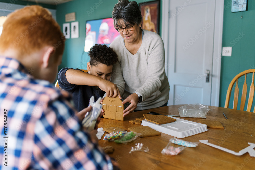 mother and sons making a gingerbread house together mother and sons making a gingerbread house together