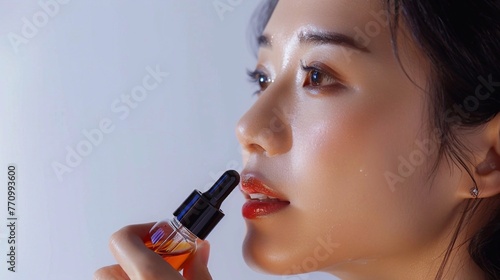 Close up Asian woman taking an oil dropper of face serum with soft blue background