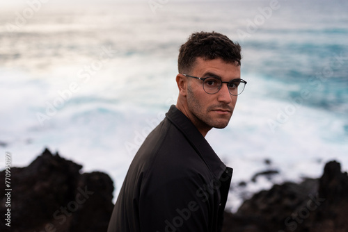 Portrait of a model facing the camera with a rough sea behind him photo