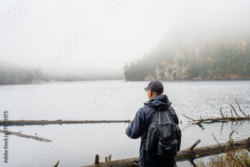 Man Looking At Misty Mountain Lake Hiking in Autumn photo