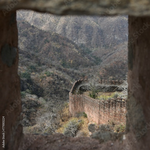 Westerly section of the mighty Kumbhalgarh stone fortress wall (Kumbhalgarh, India) seen from Badal Mahal arrow-slits against a backdrop of eroded barren dry season Aravalli hills photo