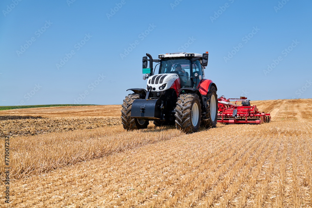 The tractor works on the stubble with reduced tillage The tractor works on the stubble with reduced tillage