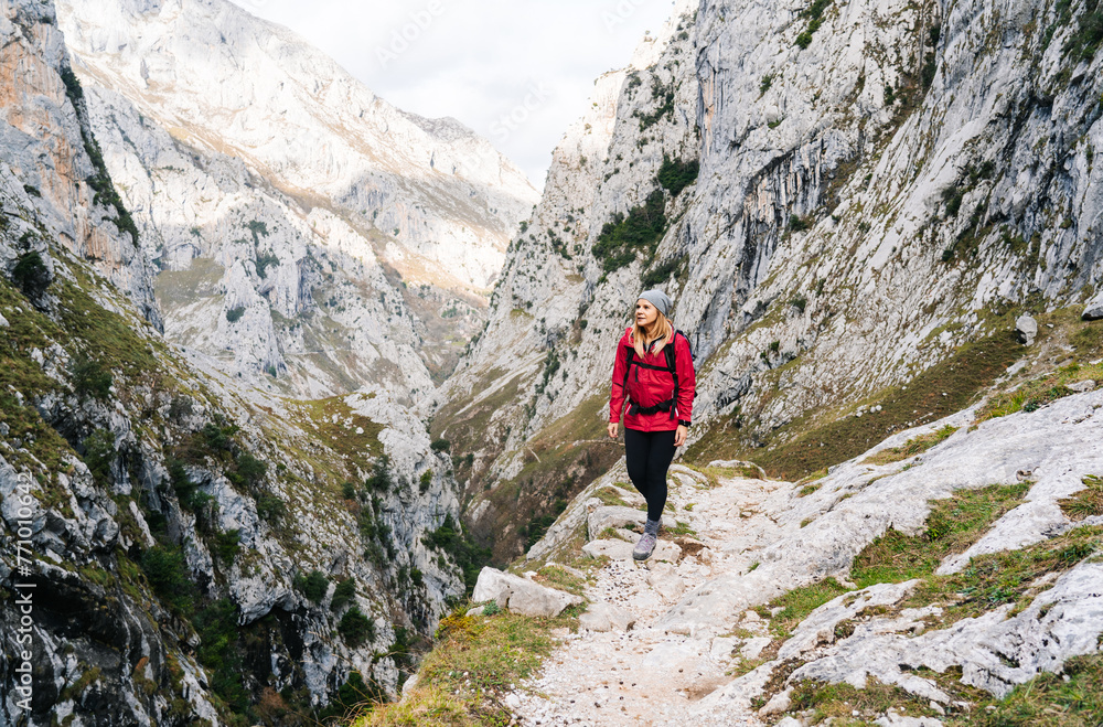 Female hiker walking on path between massive mountains Female hiker walking on path between massive mountains
