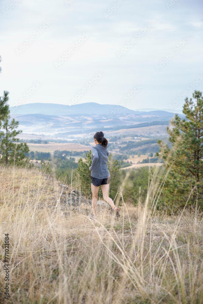 Woman jogging on mountain with scenic view in background Woman jogging on mountain with scenic view in background