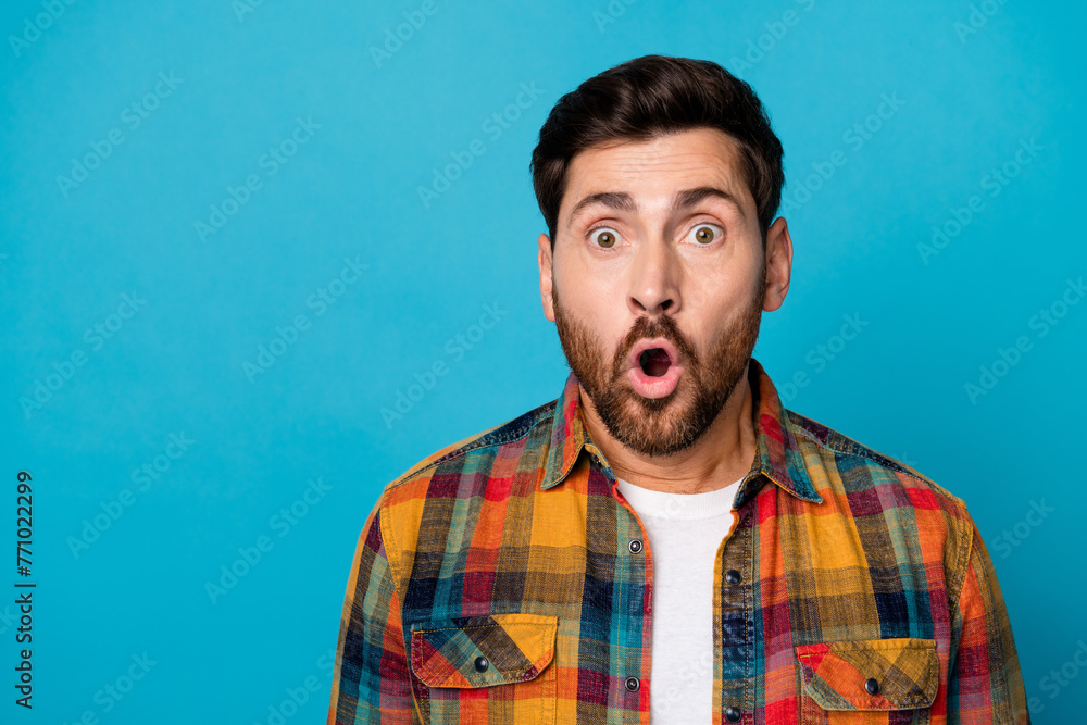 Photo of impressed funny man with beard dressed checkered shirt staring open mouth at awesome sale isolated on blue color background Photo of impressed funny man with beard dressed checkered shirt staring open mouth at awesome sale isolated on blue color background
