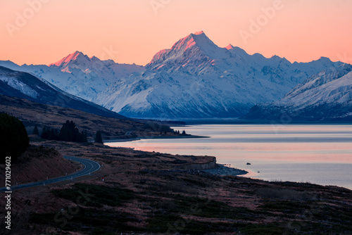 Pink light on snow covered mountains and glacial lake at sunset photo