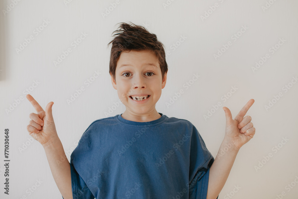 A preschool boy in a blue T-shirt on a light background shows a thumbs up A preschool boy in a blue T-shirt on a light background shows a thumbs up