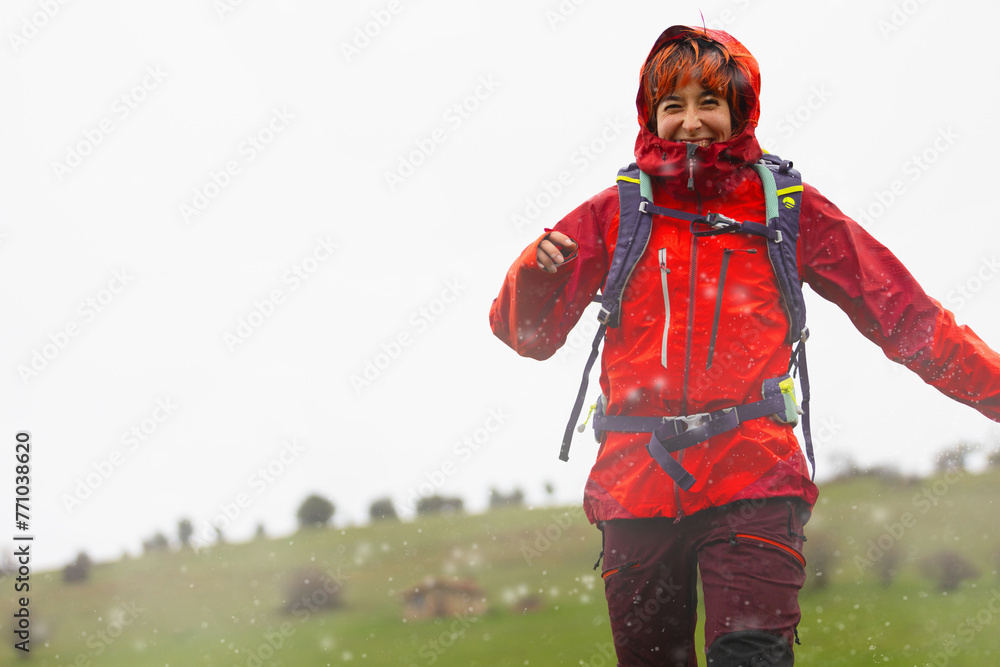 Obraz premium A woman in a red jacket and black pants is walking in the snow. She is smiling and she is enjoying herself