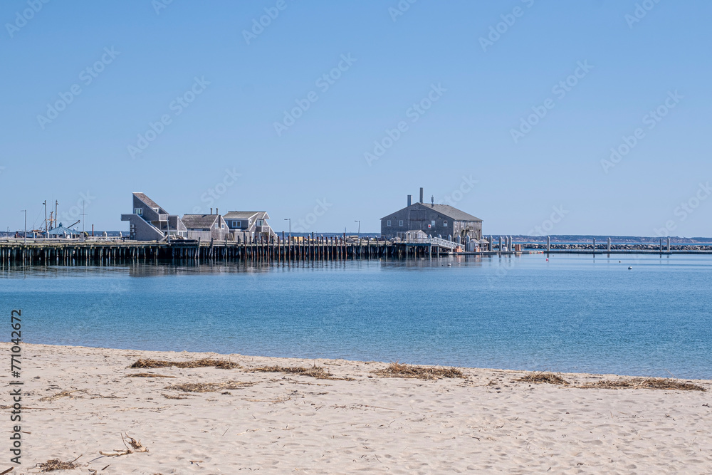 Landscape view of a long pier over blue ocean water and sandy shore in Provincetown, Massachusetts