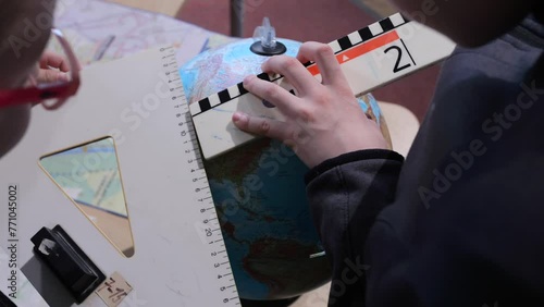 Student Hands Using a Clapperboard and a Globe for Geography Lesson Project