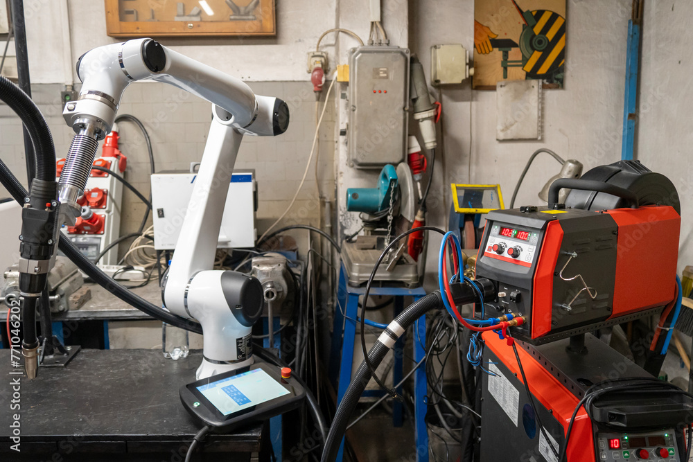A modern welding robot in an old crowded welding workshop A modern welding robot in an old crowded welding workshop