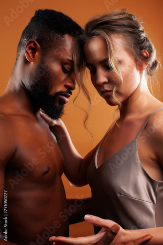 Young pretty couple diverse races together posing sensitive on brown background, lifestyle people