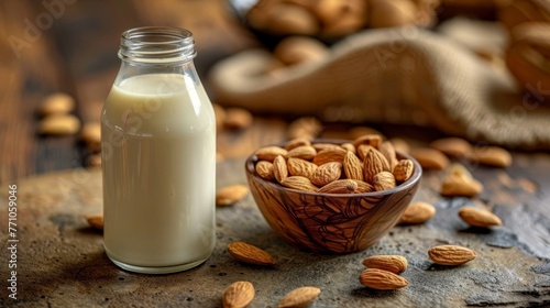 Organic almond milk in glass bottle with raw almonds on stone table in kitchen setting