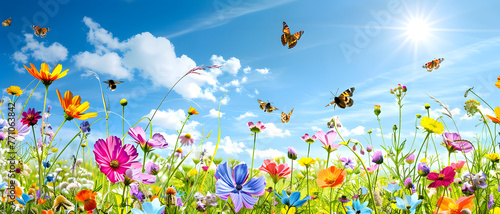 A beautiful, picturesque scene of colorful wildflowers and fluttering butterflies under a bright blue sky with sun rays