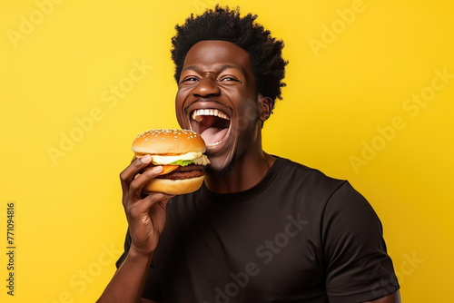 Joyful Man Enjoying a Delicious Burger  Bright Yellow Background for Fun Fast Food Concept