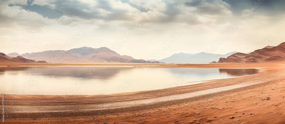 A pristine lake stands in the midst of the desert, surrounded by majestic mountains and lush green trees, creating a stunning natural landscape against the clear blue sky