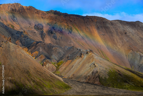 A rainbow at the rugged, multi-coloured rhyolite hills of Vondugil valley, Landmannalaugar, Fjallabak Nature Reserve, Central Highlands, Iceland.