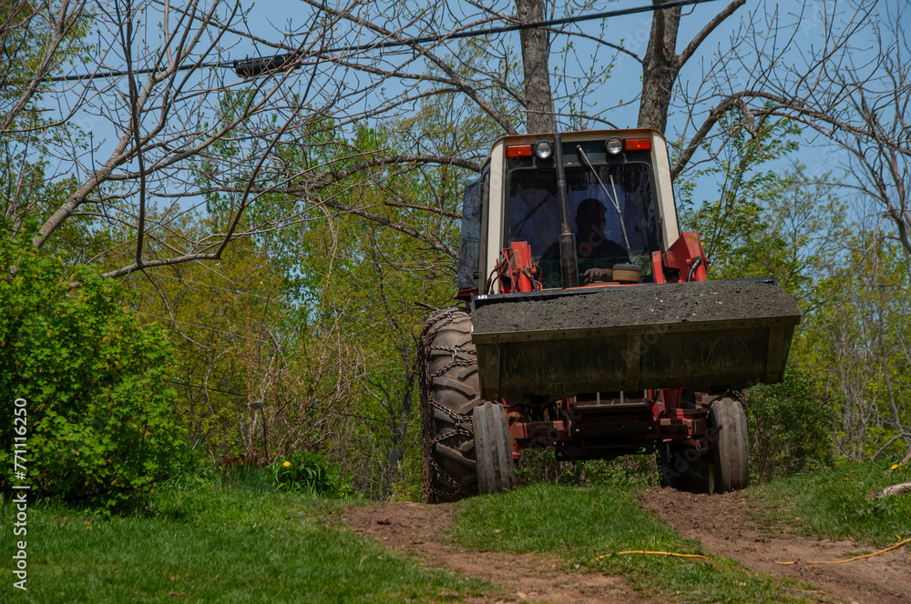 A man driving a red tractor full of gravel in the bucket during spring on a sunny day A man driving a red tractor full of gravel in the bucket during spring on a sunny day
