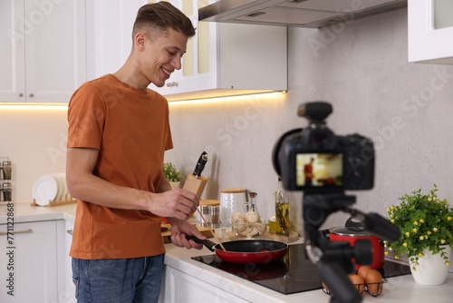 Fototapeta Naklejka Na Ścianę i Meble -  Smiling food blogger cooking while recording video in kitchen