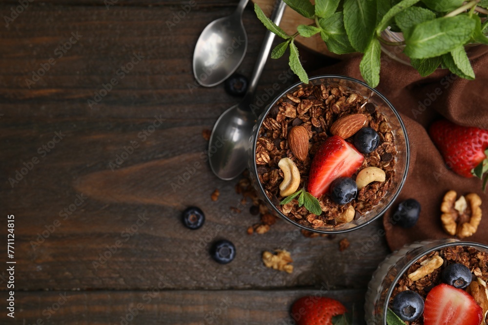 Tasty granola, berries, nuts and mint on wooden table, flat lay. Space for text