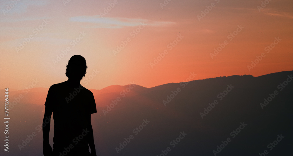 Silhouette of a young man standing at sunset