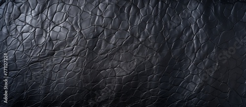 A detailed closeup of a black leather texture, showcasing its rich monochrome pattern and the contrast of darkness. The texture resembles fur or metal with a smooth and sleek appearance