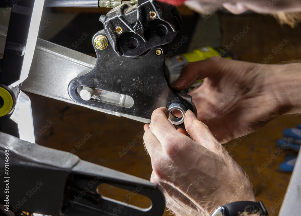 The master is busy repairing a mountain bike in the garage. wheel, chain, tire, engine and other elements
