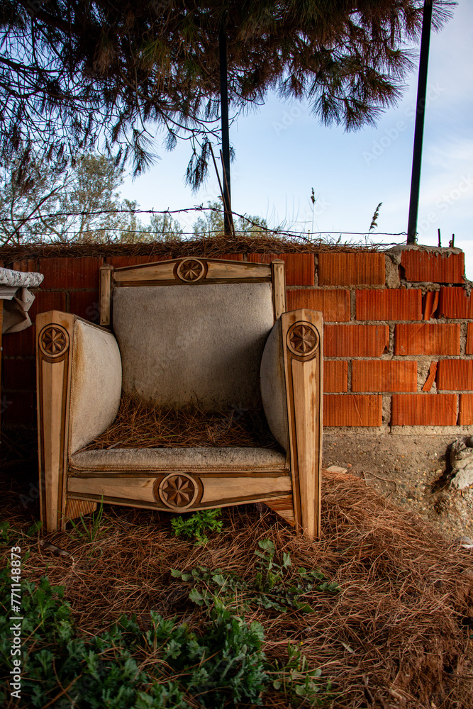 Wooden furniture made of natural materials in the garden. Abandoned old armchair on the beach near the brick wall.Vintage furniture on the beach. Wooden furniture made of natural materials in the garden. Abandoned old armchair on the beach near the brick wall.Vintage furniture on the beach.