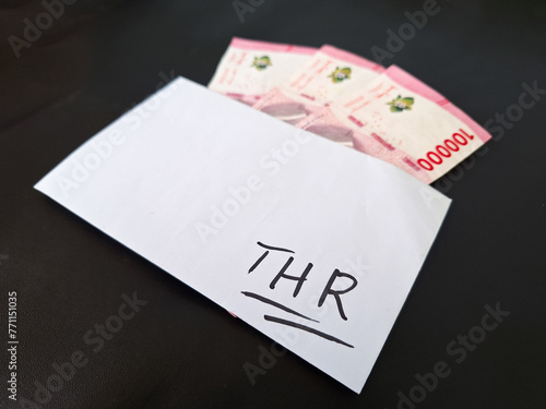 Envelope and three hundred thousand rupiah in cash. THR (Tunjangan Hari Raya) or Religious Holiday Allowance Concept in Indonesia. photo