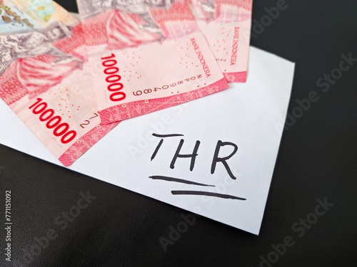 Envelope and three hundred thousand rupiah in cash. THR (Tunjangan Hari Raya) or Religious Holiday Allowance Concept in Indonesia. photo