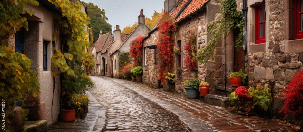 A charming cobblestone street in a small town, lined with houses adorned with colorful flowers and surrounded by lush green trees and grass in a quaint neighborhood