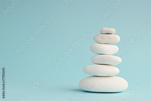 Stack of White Sea Pebble Stones on Light Blue Background. Simple Yet Elegant Concept with Copy Space on Right Side. Pastel Colors Add Serenity to the Composition.