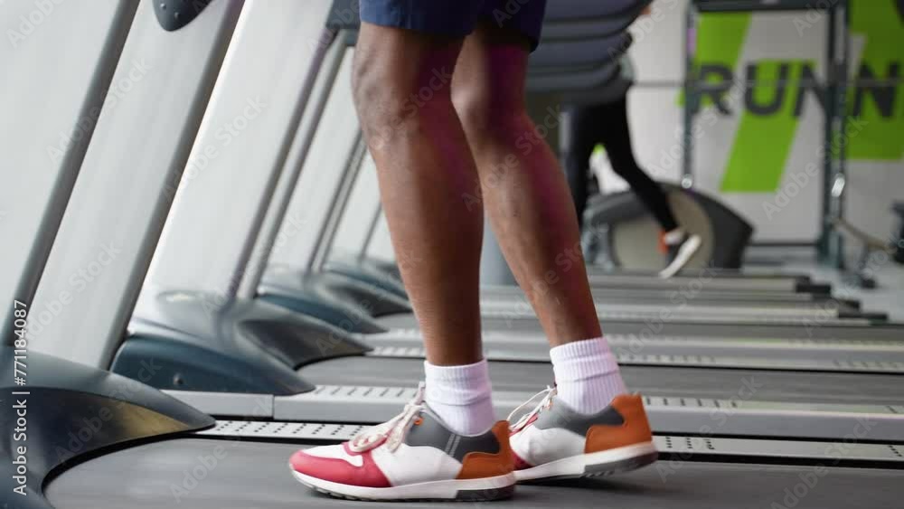 Young man running on treadmill at gym, close up of legs Young man running on treadmill at gym, close up of legs