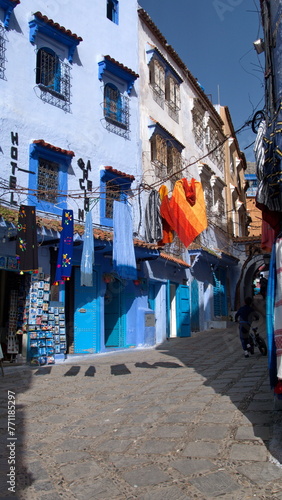 Colorful textiles hanging above an alley in Chefchaouen, Morocco © Angela