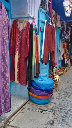 Colorful display of clothing and textiles in front of a shop in the medina, in Chefchaouen, Morocco © Angela