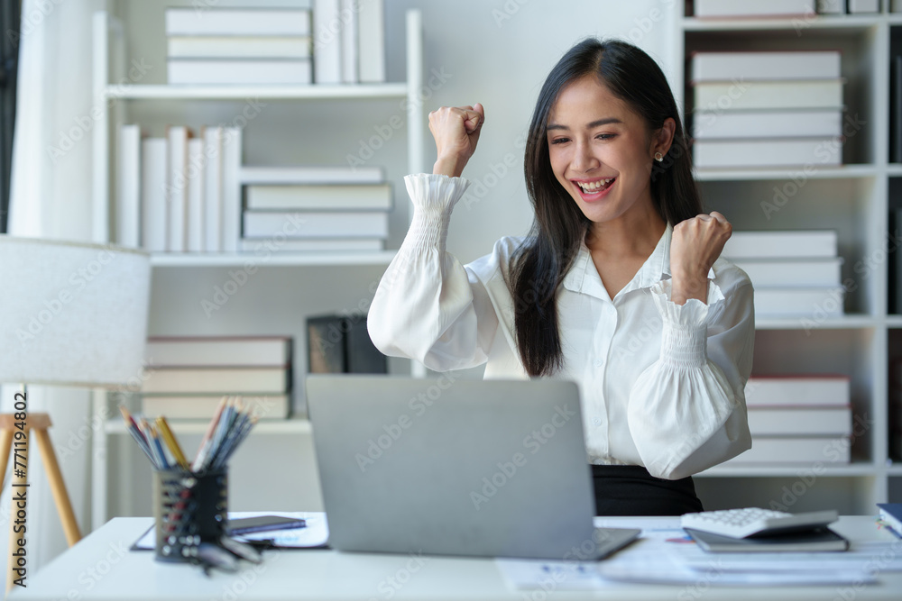 Asian businesswoman, office worker happy and cheerful while receiving recognition on laptop computer, expressing excitement over success and company annual bonus. Success concept. Asian businesswoman, office worker happy and cheerful while receiving recognition on laptop computer, expressing excitement over success and company annual bonus. Success concept.