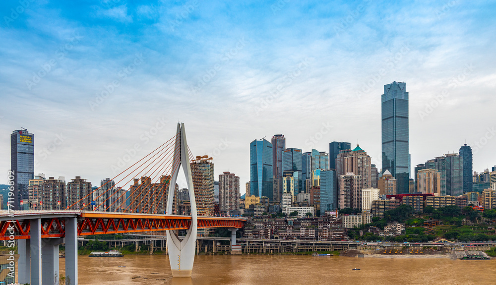 Fototapeta premium The Qiansimen Bridge, the Yangtze River Bridge in Chongqing, China, features vehicles driving on the bridge and towering skyscrapers in the distance