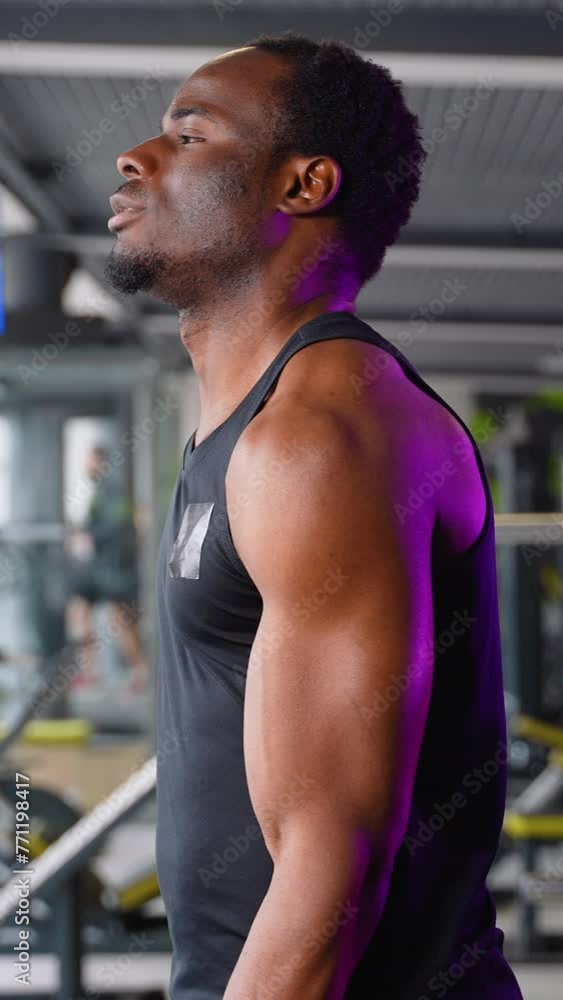 Young man training biceps muscles with dumbbell in fitness gym. Vertical video Young man training biceps muscles with dumbbell in fitness gym. Vertical video