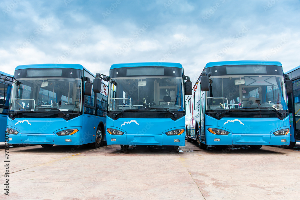Many electric driven new energy buses are neatly parked in outdoor parking lots