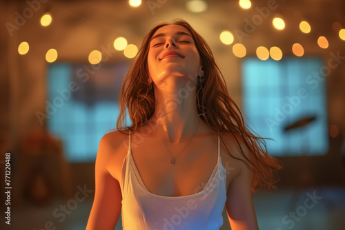 A woman dances in a room lit by lamps on the ceiling