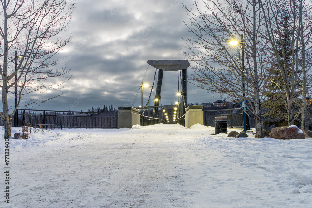 Fort Edmonton foot bridge in night light with dark sky clouds and snow cover Fort Edmonton foot bridge in night light with dark sky clouds and snow cover