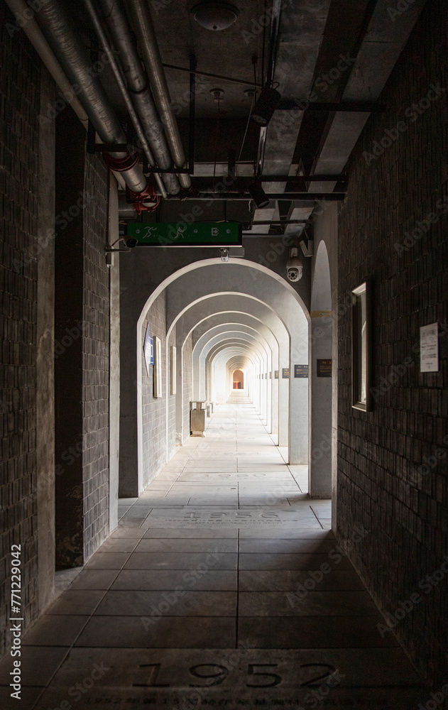 The corridor within a long ancient building has many arched doors