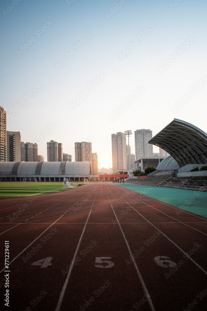 Obraz premium In the city, sunlight shines on outdoor sports stadiums, and outside the stadiums are towering skyscrapers