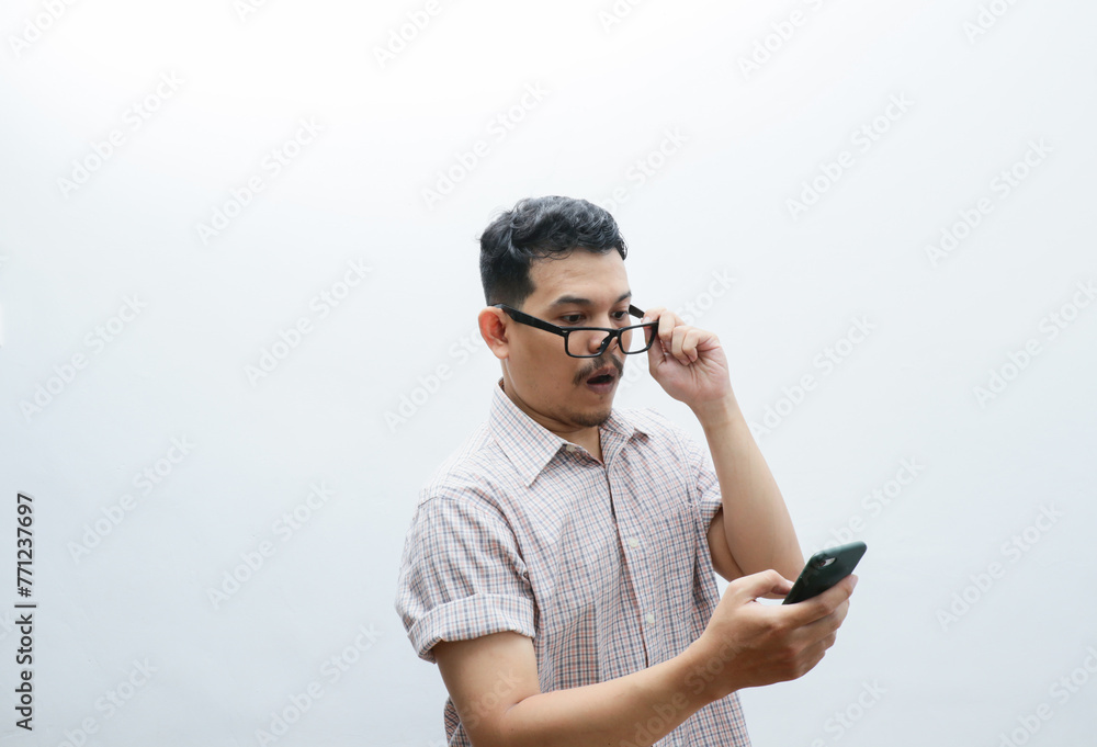 Asian man holding mobile phone and feeling shocked portrait white isolated Asian man holding mobile phone and feeling shocked portrait white isolated