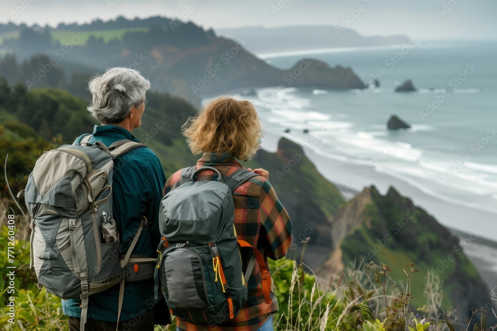 Elderly senior smiling active couple with backpacks enjoying hiking and walking along coastline near mountains and sea or ocean, active retirement lifestyle filled with outdoor adventures. Elderly senior smiling active couple with backpacks enjoying hiking and walking along coastline near mountains and sea or ocean, active retirement lifestyle filled with outdoor adventures.
